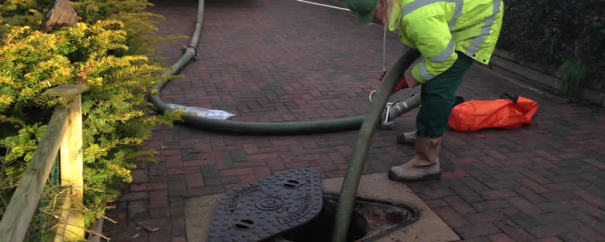 Septic tank cleaning technician servicing a septic tank with a vacuum hose in Wellesley, MA